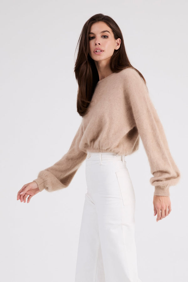 Three-quarter view of the Stevie beige cashmere sweater with gathered waist detail.