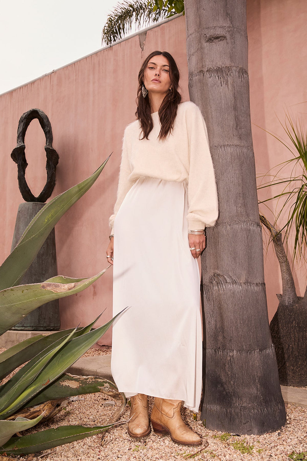 Woman wearing the Stevie ivory cashmere sweater by Beryll with a flowing ivory dress.