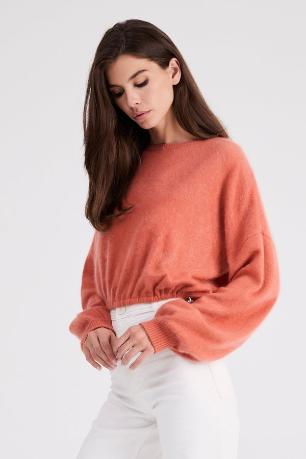 Three-quarter view of the Stevie coral cashmere sweater with gathered waist detail.